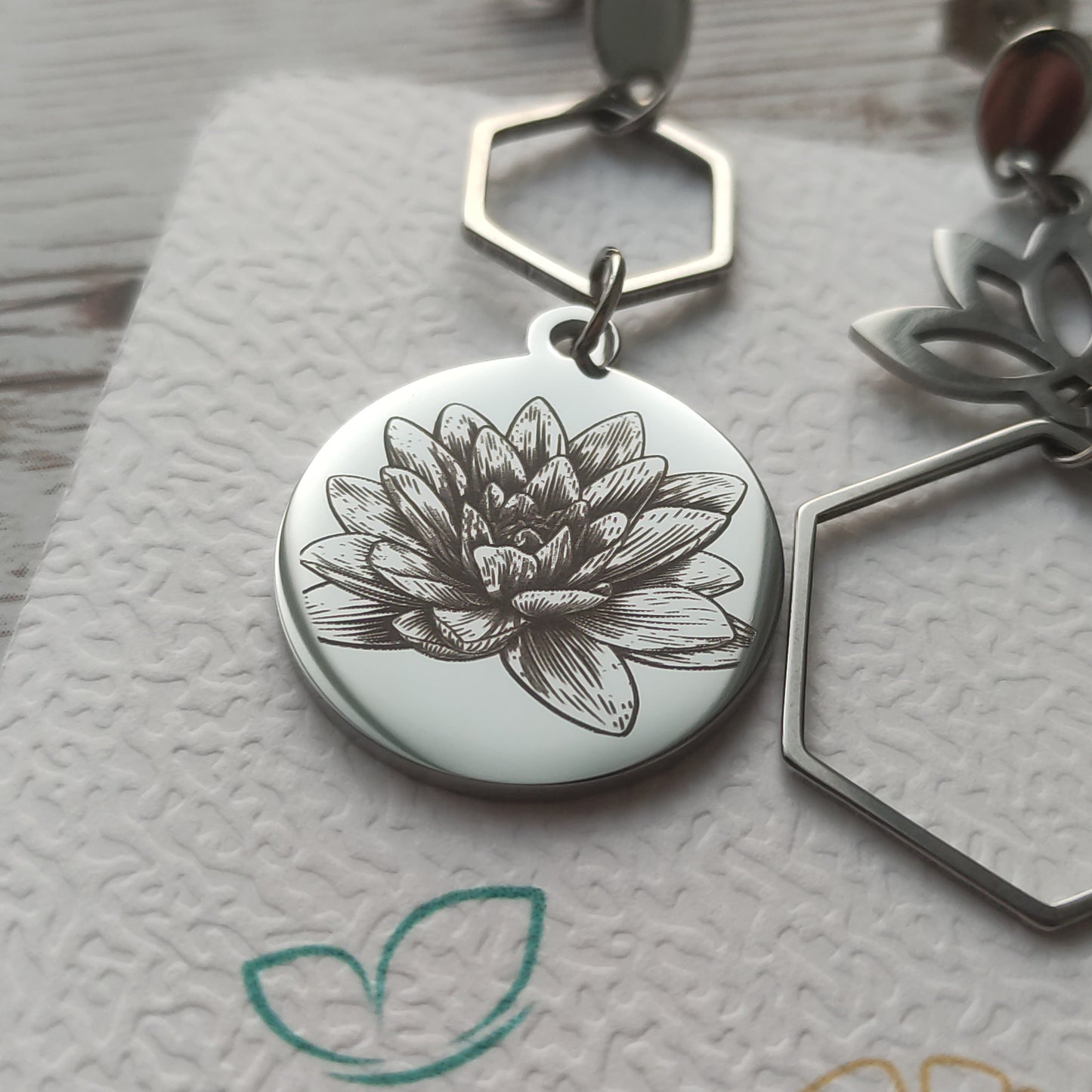 Détail d'une boucle d'oreille fleur de lotus avec gravure de précision gris foncé sur acier inoxydable.