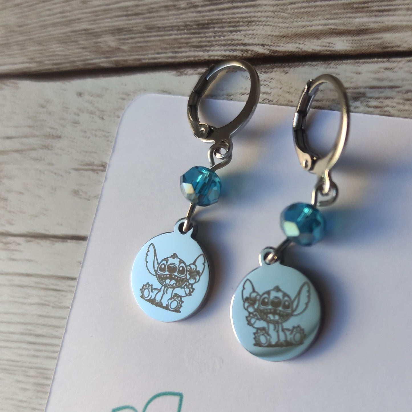 Boucles d'oreilles pendantes en acier inoxydable avec gravure laser de Stitch et une fleur, surmontées d'un cristal bleu