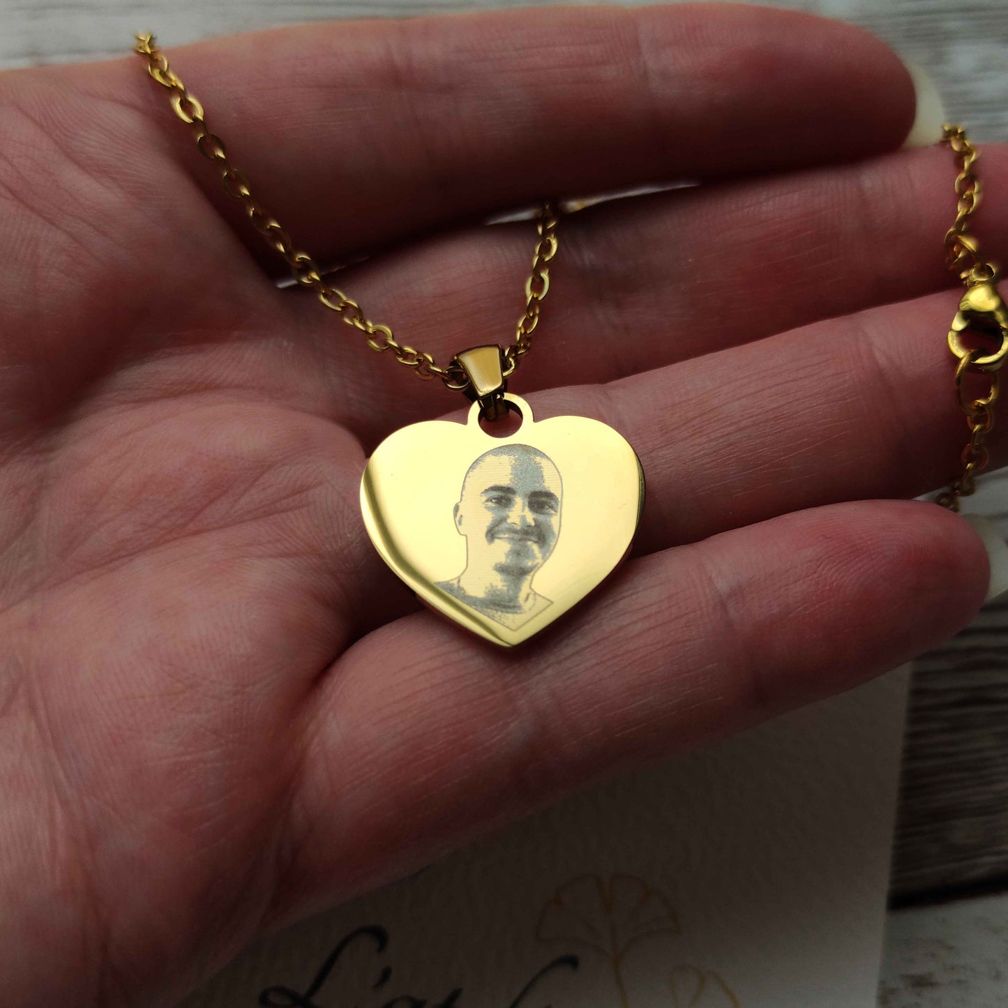 Zoom sur la gravure laser haute définition d'une photo d'enfant sur un pendentif cœur en acier inoxydable.