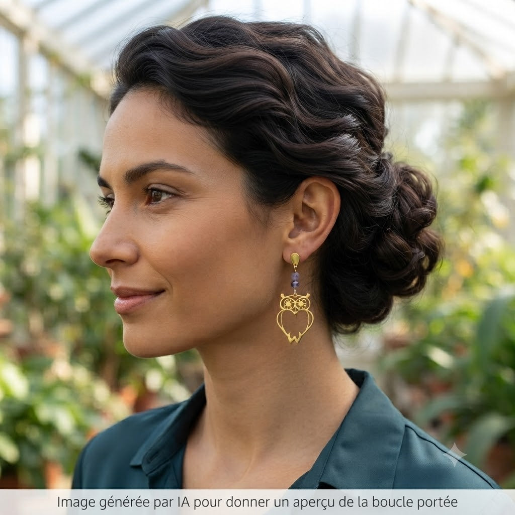 Femme portant des boucles d'oreilles pendantes hibou dorées en extérieur.