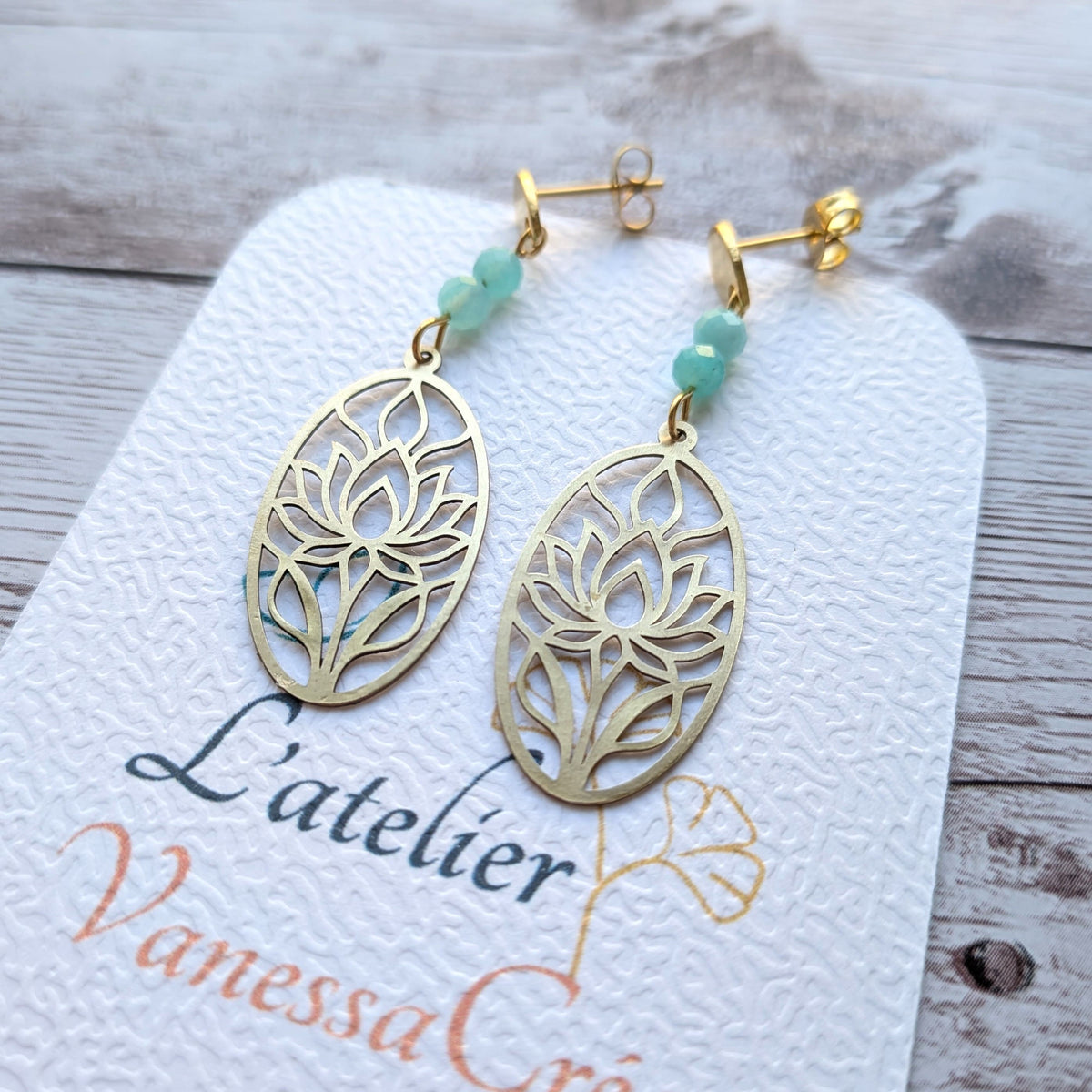 Gros plan sur la découpe du lotus en laiton et les perles facettées d'amazonite des boucles d'oreilles faites main.