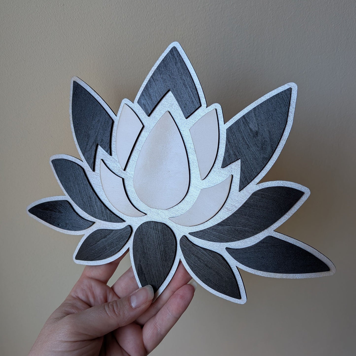 Fleur de lotus en bois tricolore tenue en main pour échelle