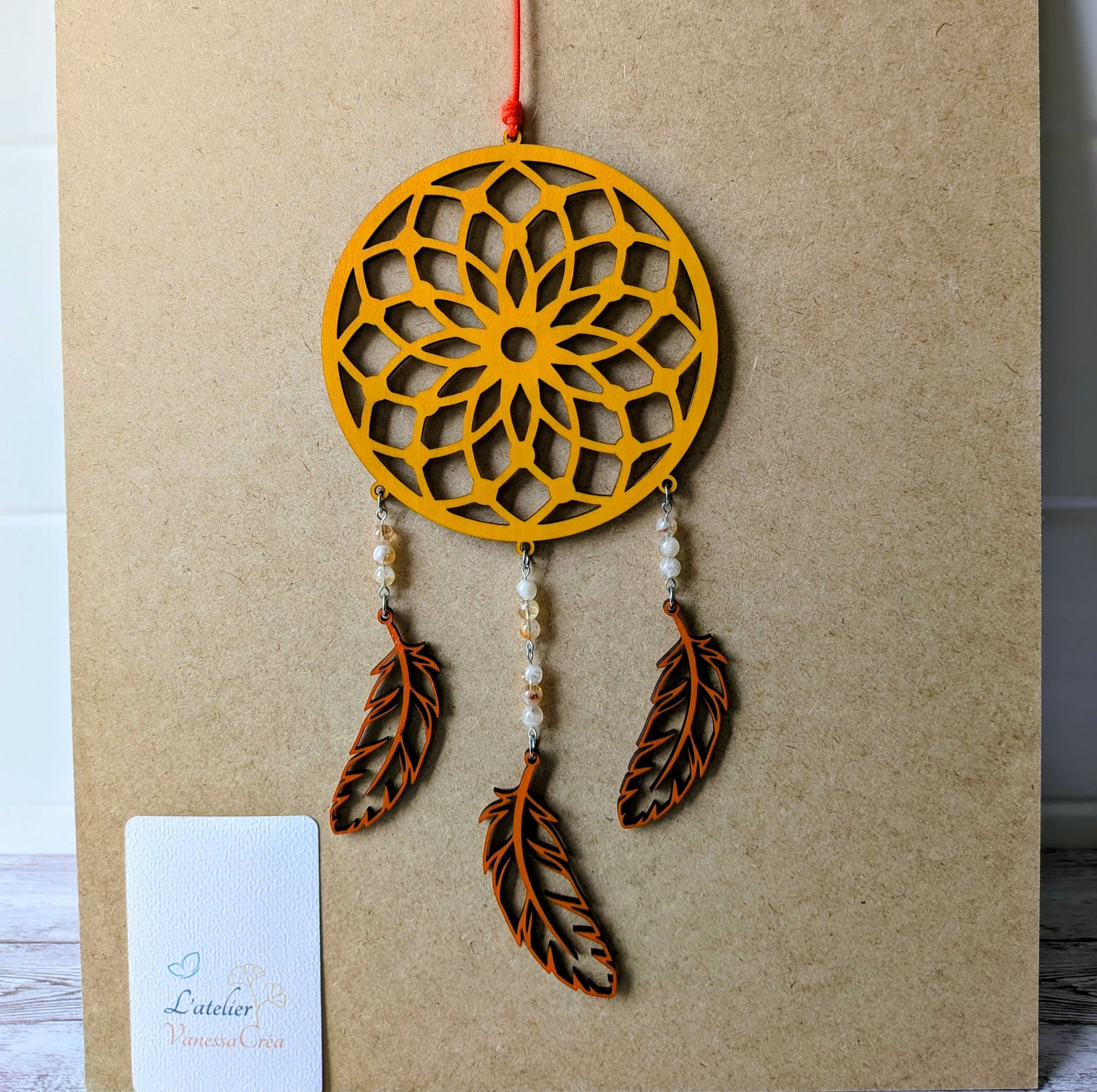 Attrape-rêve artisanal en bois de tilleul jaune safran avec plumes découpées et perles de citrine.