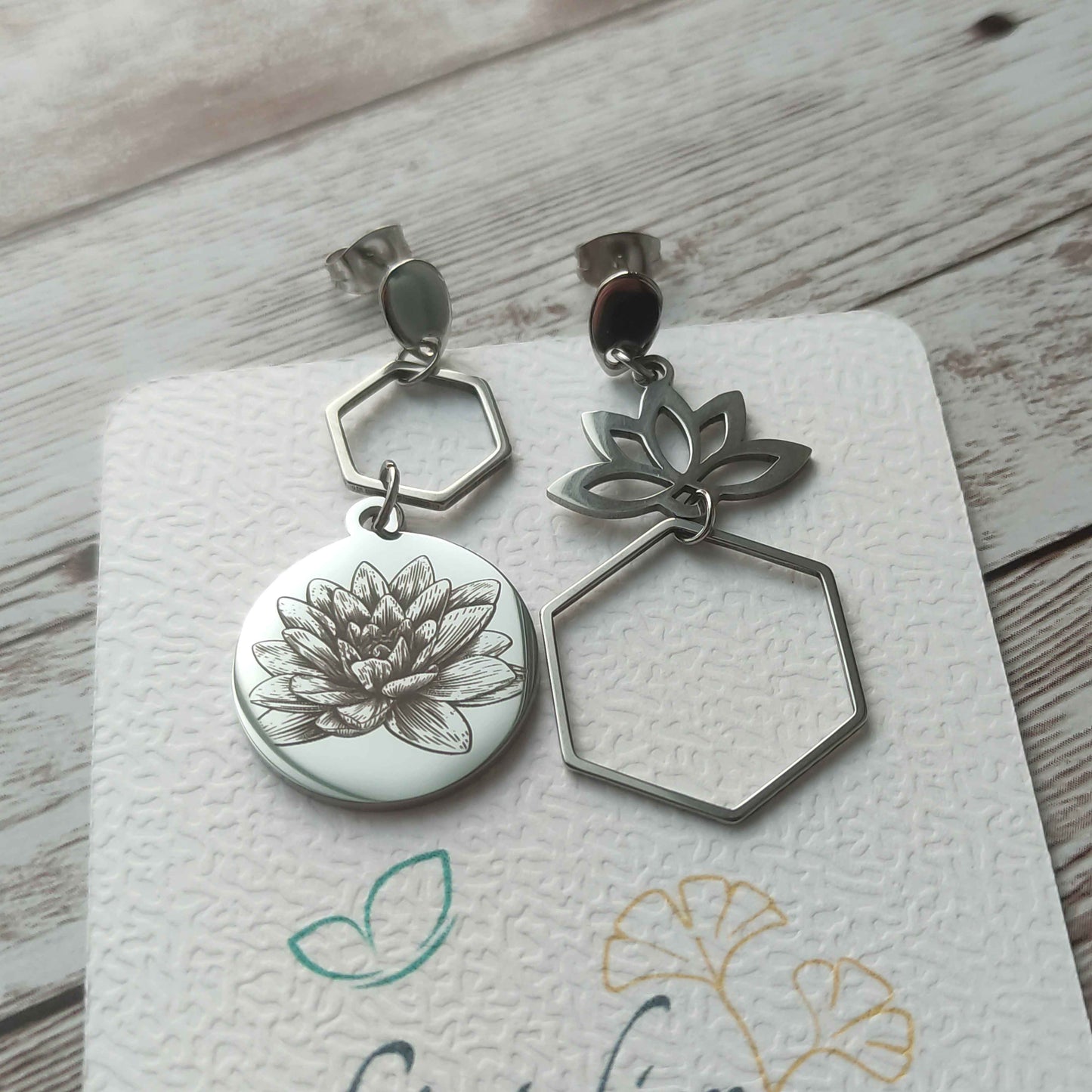 Paire de boucles d'oreilles asymétriques lotus en acier inoxydable portée par une femme, finition miroir.
