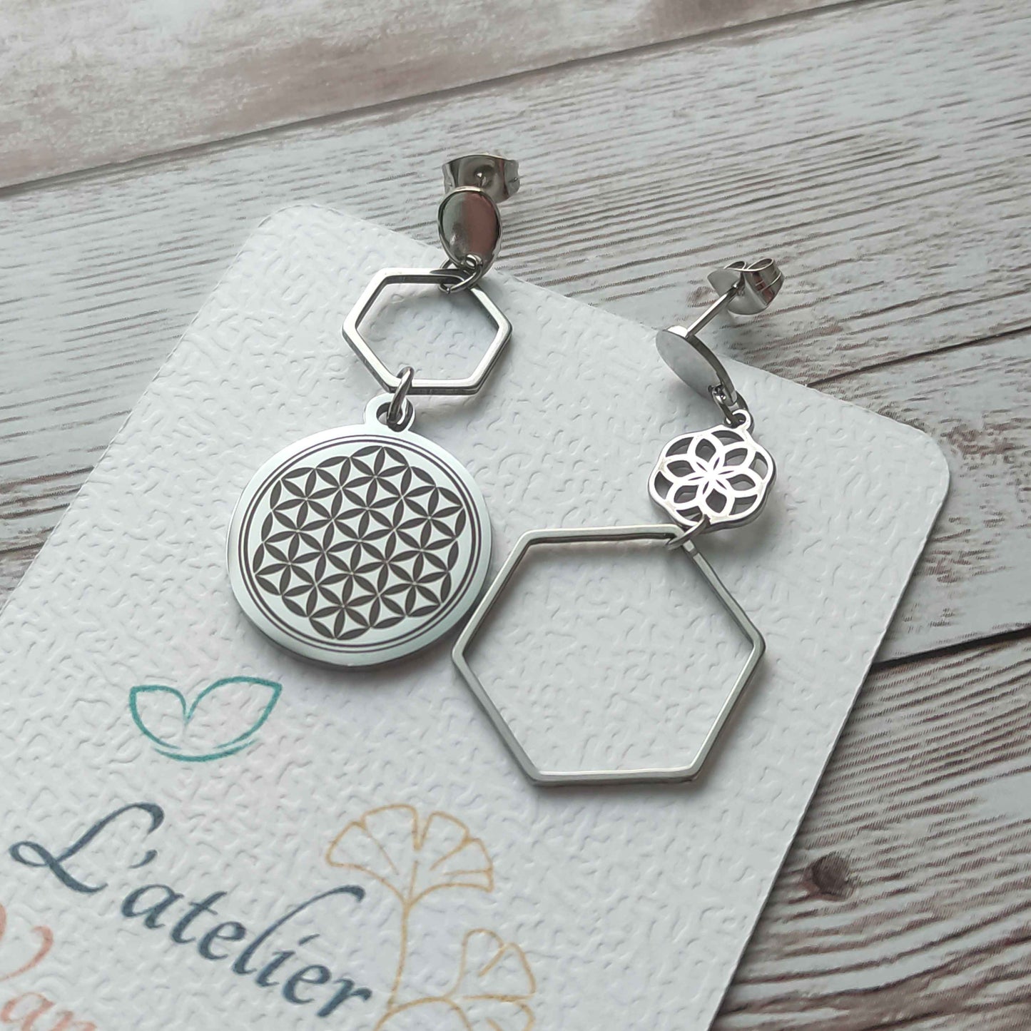 Paire de boucles d'oreilles asymétriques Fleur de Vie en acier inoxydable avec une boucle gravée et une boucle ajourée, fini miroir.