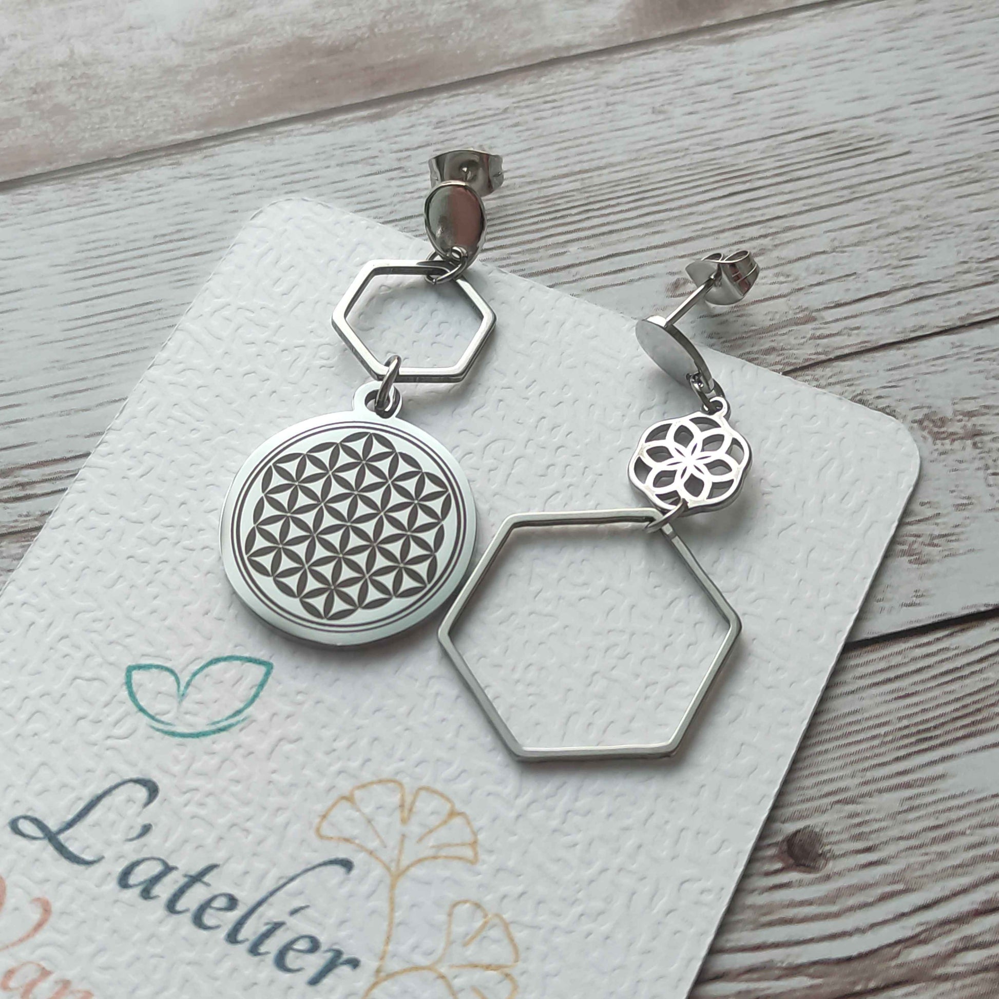 Paire de boucles d'oreilles asymétriques Fleur de Vie en acier inoxydable avec une boucle gravée et une boucle ajourée, fini miroir.
