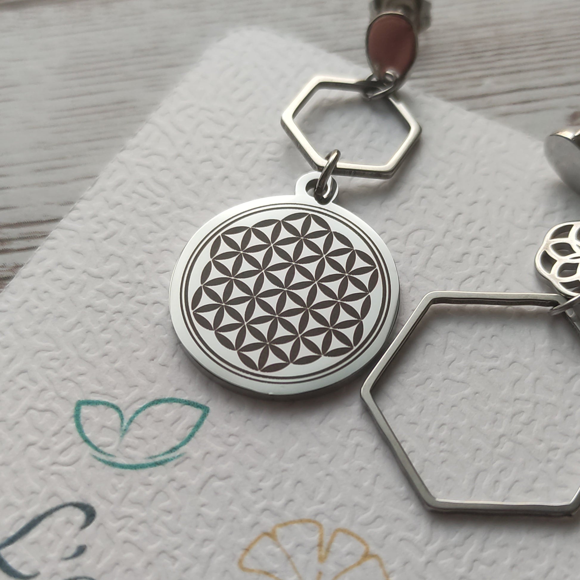 Détail de la gravure artisanale de précision sur acier inoxydable gris foncé représentant la Fleur de Vie.