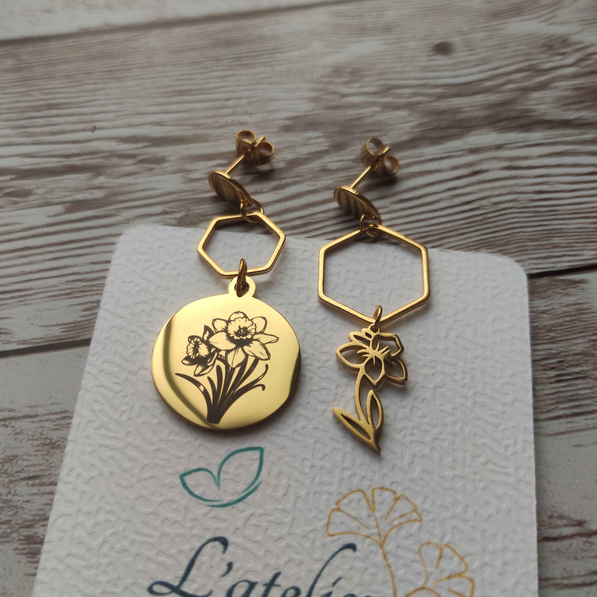 Paire de boucles d'oreilles asymétriques jonquilles en acier inoxydable effet miroir, une boucle gravée et une boucle ajourée.
