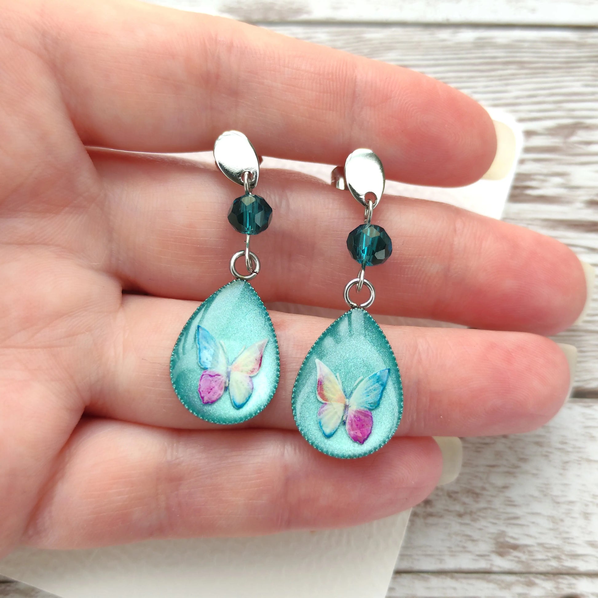 Détail d'un papillon capturé dans une résine nacrée vert pastel avec cristal à facettes brillant.