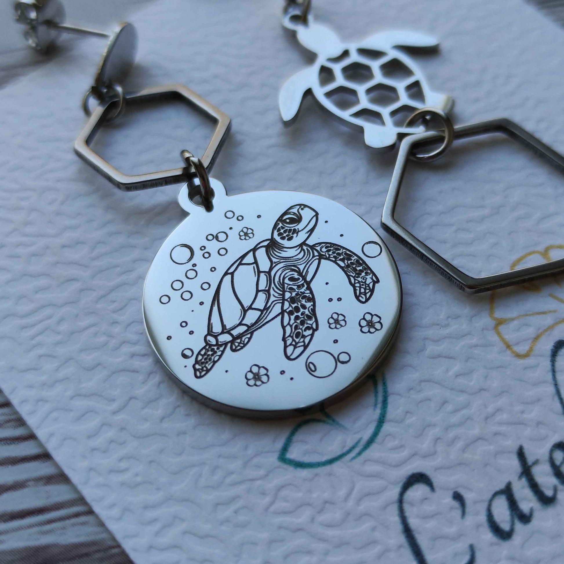 Détail de la gravure laser de précision sur une puce d'oreille tortue en acier inoxydable poli miroir.