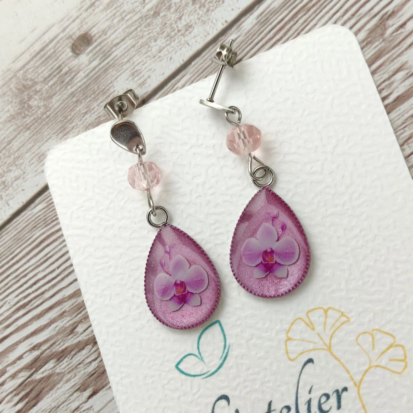 Boucles d'oreilles goutte en résine avec véritable orchidée rose pastel et clou en acier inoxydable argenté.
