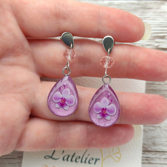 Détail d'une boucle d'oreille fleur orchidée résine nacrée avec cristal étincelant et finitions argentées.