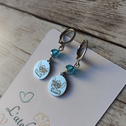 Boucles d'oreilles pendantes en acier inoxydable avec gravure laser de Stitch et une fleur, surmontées d'un cristal bleu