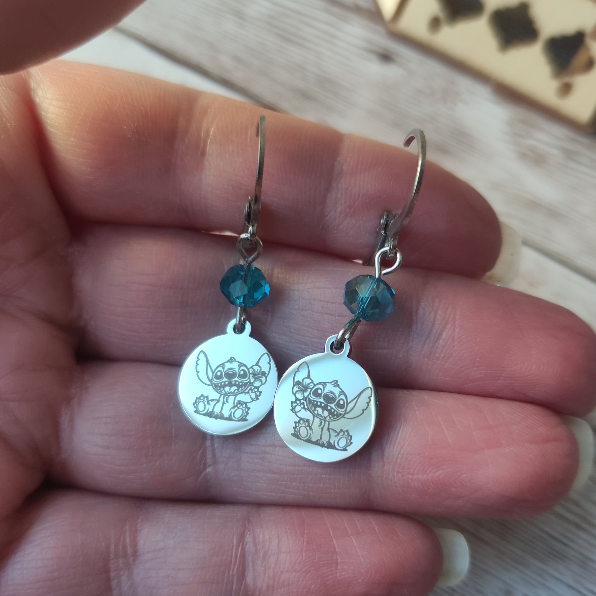 Boucles d'oreilles pendantes en acier inoxydable avec gravure laser de Stitch et une fleur, surmontées d'un cristal bleu