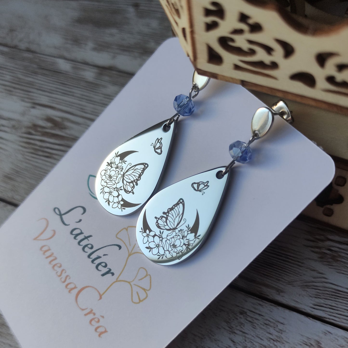 Boucles d'oreilles pendantes en acier inoxydable avec cristal à facettes et goutte gravée d'une lune fleurie et d'un papillon.