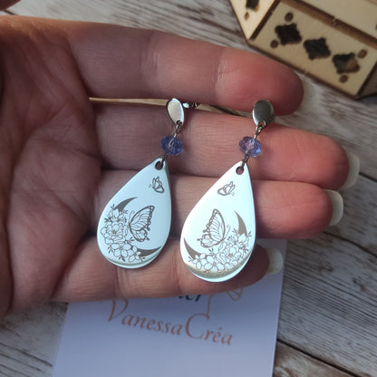 Boucles d'oreilles pendantes en acier inoxydable avec cristal à facettes et goutte gravée d'une lune fleurie et d'un papillon.