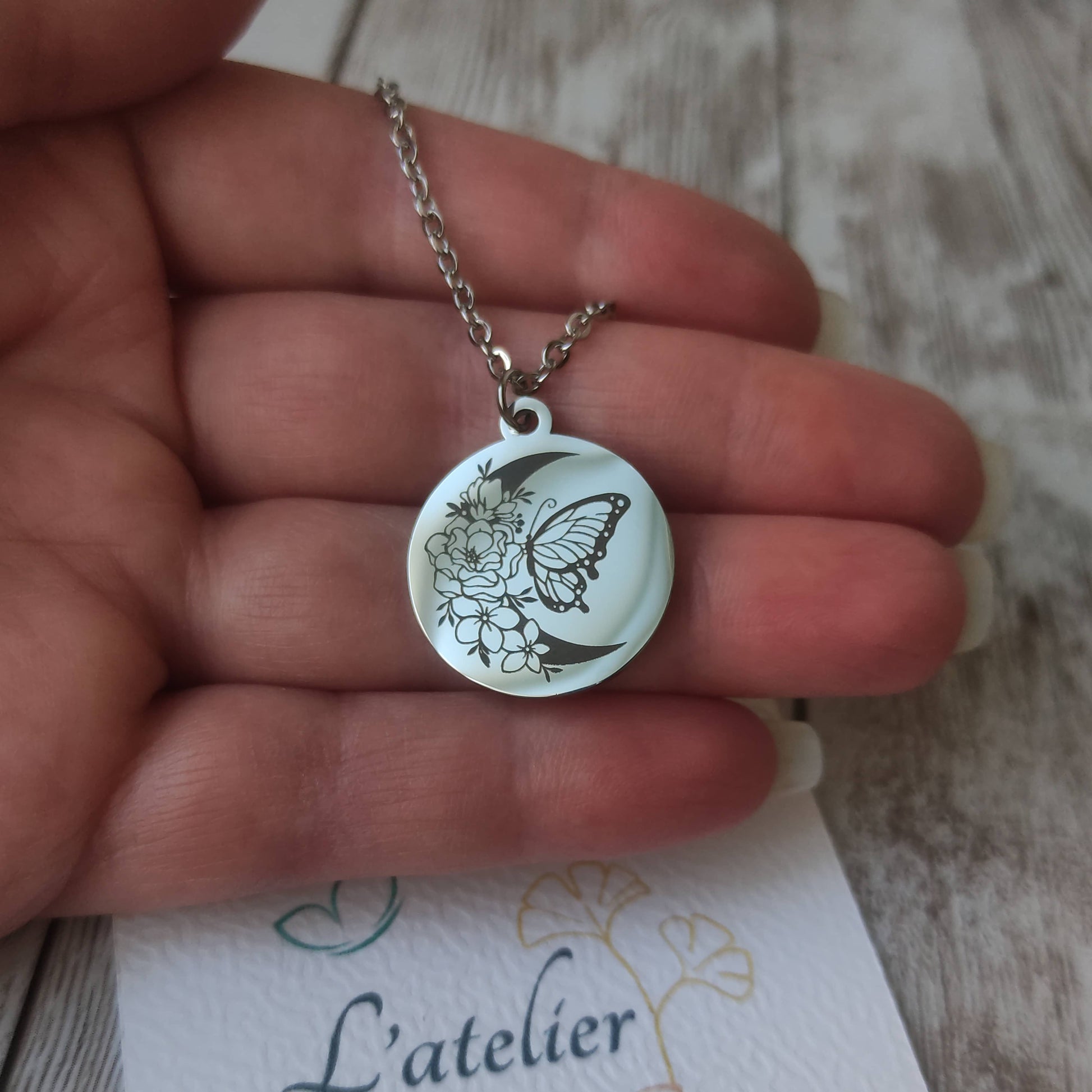 Collier en acier inoxydable argenté poli miroir avec gravure laser d'un papillon sur une lune fleurie, pendentif rond 20mm.
