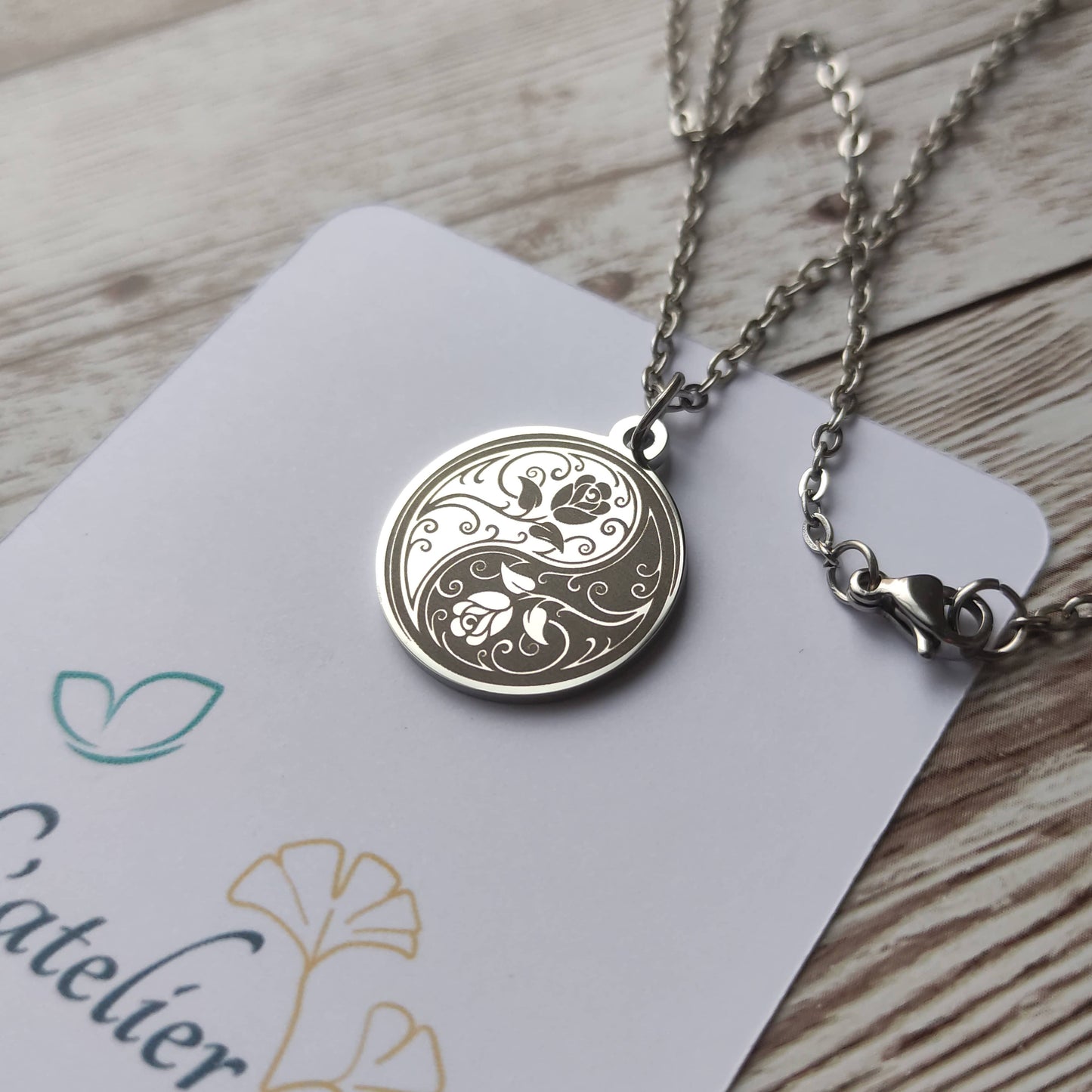 Collier médaille ronde en acier poli miroir avec gravure laser d'un symbole Yin Yang entrelacé de roses.