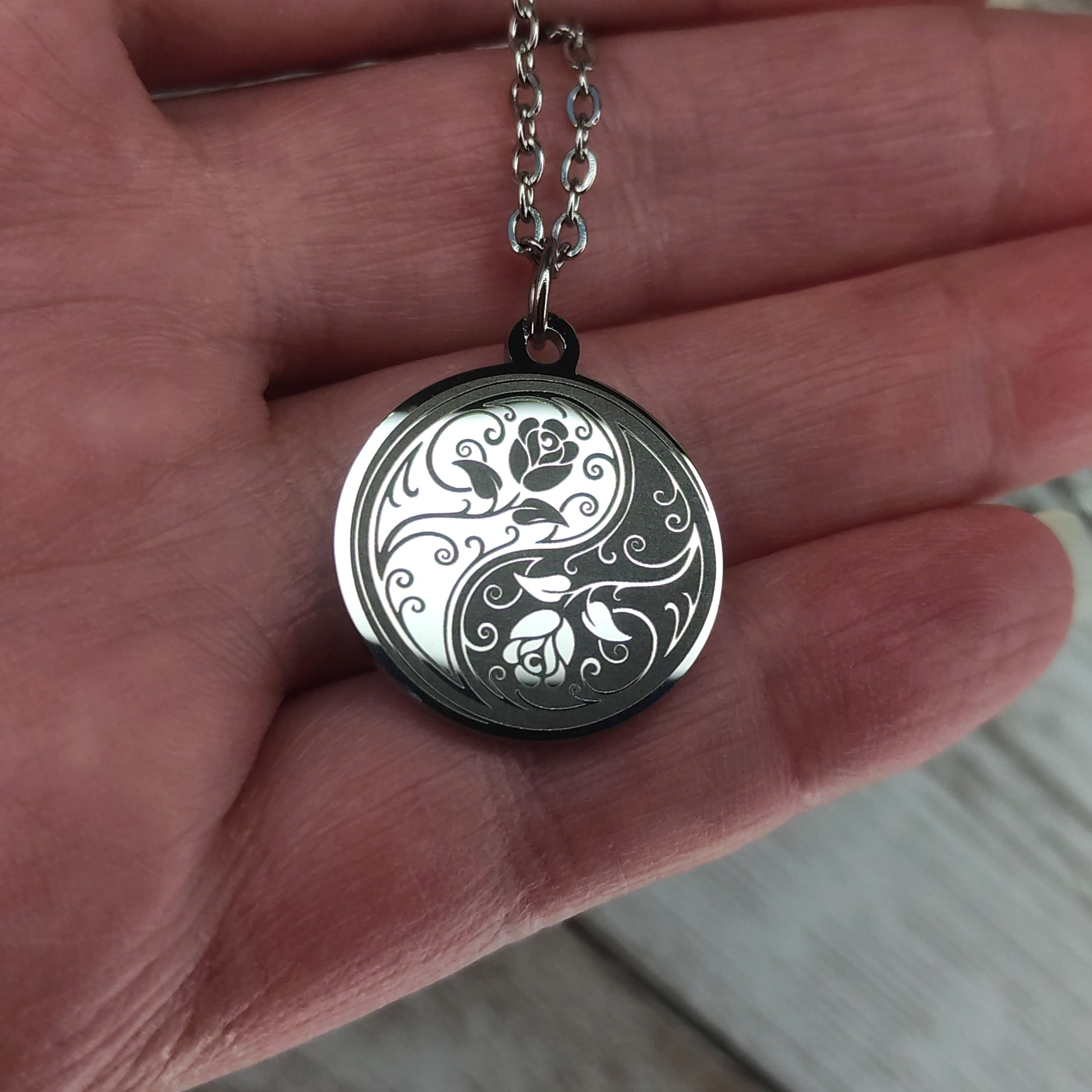 Collier médaille ronde en acier poli miroir avec gravure laser d'un symbole Yin Yang entrelacé de roses.