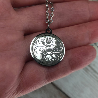 Collier médaille ronde en acier poli miroir avec gravure laser d'un symbole Yin Yang entrelacé de roses.