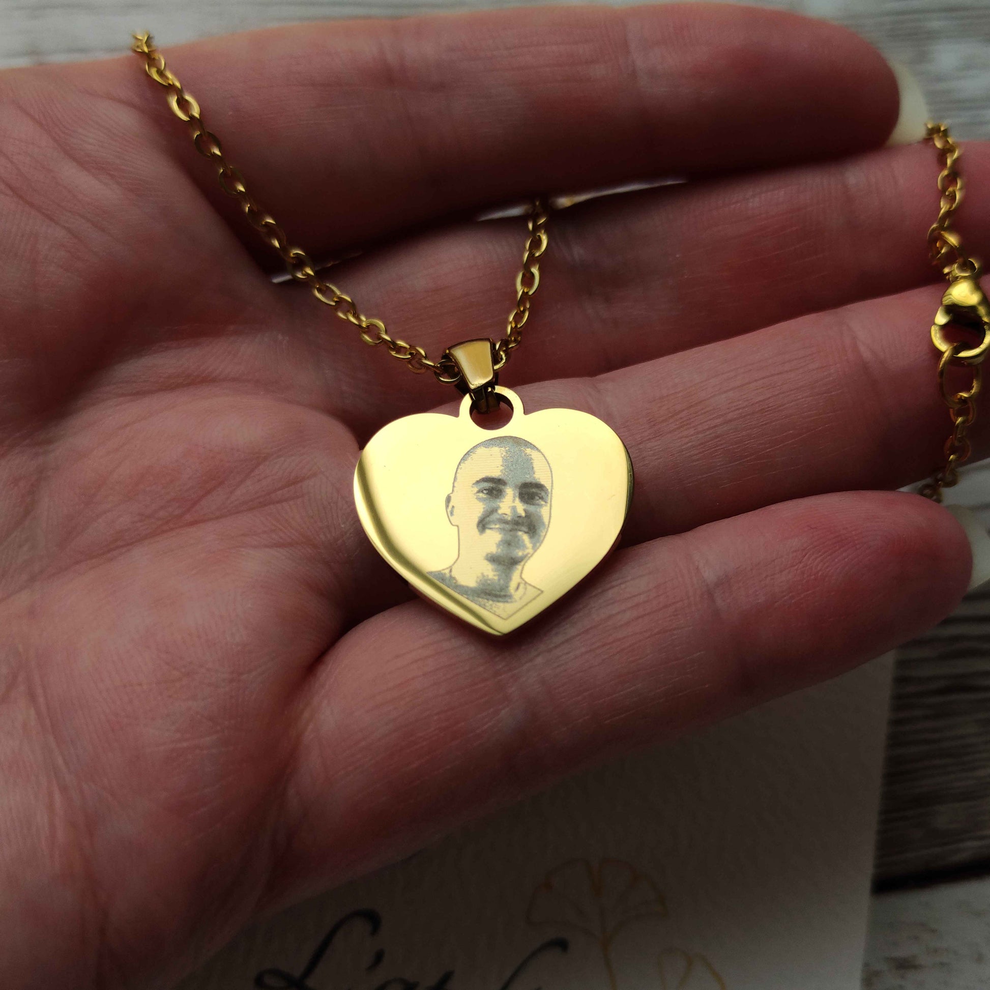 Zoom sur la gravure laser haute définition d'une photo d'enfant sur un pendentif cœur en acier inoxydable.