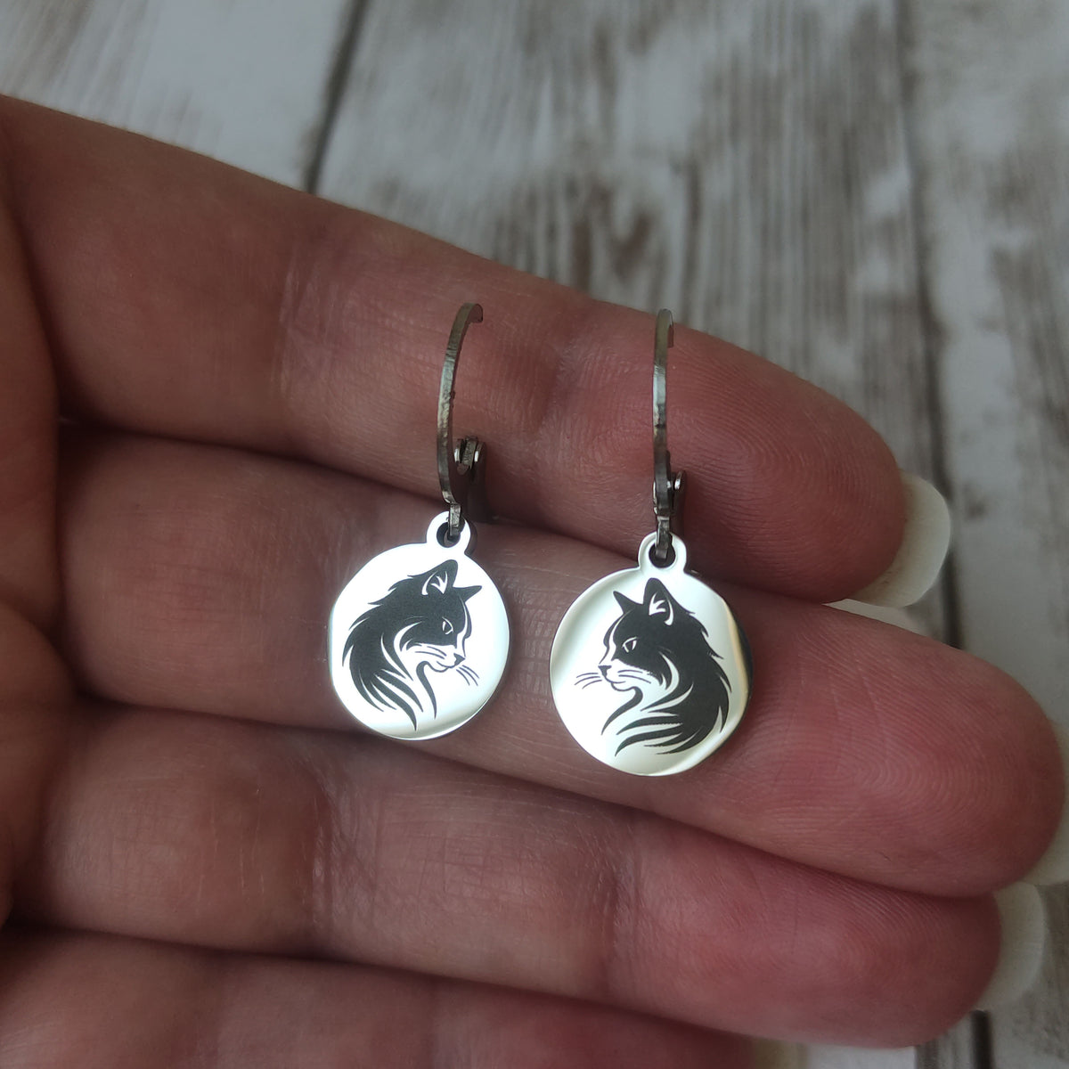 Paire de boucles d'oreilles dormeuses chat en acier inoxydable poli miroir avec gravure laser tête de chat sur médaillon rond.