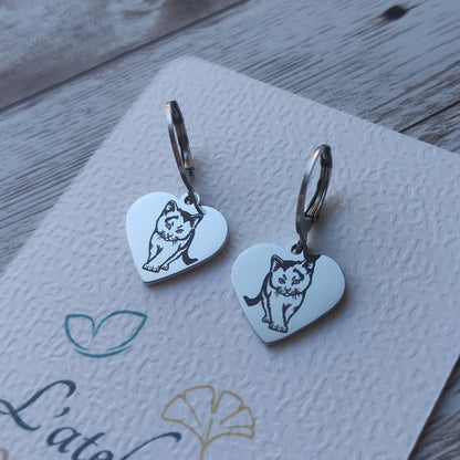 Paire de boucles d'oreilles dormeuses en acier inoxydable avec pendentif coeur poli miroir et gravure laser d'un petit chat.