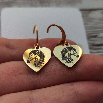 Paire de boucles d'oreilles dormeuses en acier inoxydable avec pendentif coeur poli miroir gravé d'une tête de cheval et de fleurs.