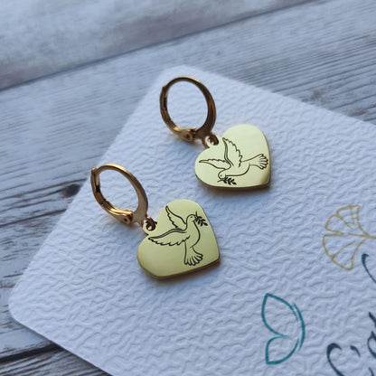 Paire de boucles d'oreilles dormeuses coeur colombe acier inoxydable poli miroir sur fond blanc.