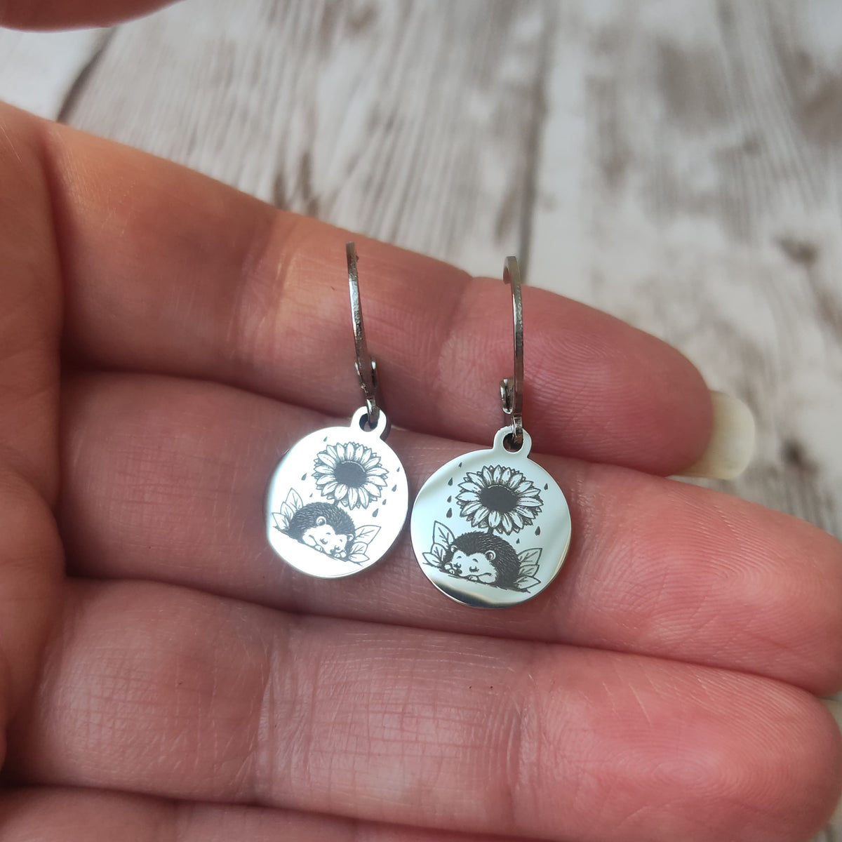Boucles d'oreilles dormeuses en acier inoxydable poli miroir avec gravure laser d'un hérisson et d'un tournesol.
