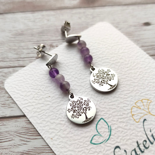 Paire de boucles d'oreilles pendantes avec motif Arbre de Vie gravé et perles d'améthyste sur carte de présentation L'atelier Vanessa Créa.