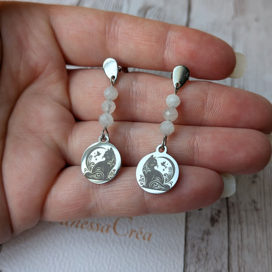 Boucles d'oreilles chat en acier inoxydable tenues délicatement dans la main.