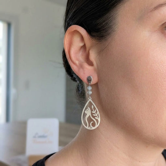 Boucles d'oreilles chat et feuillage ajouré en acier inoxydable et labradorite portées, mettant en valeur leur finesse et leur longueur.