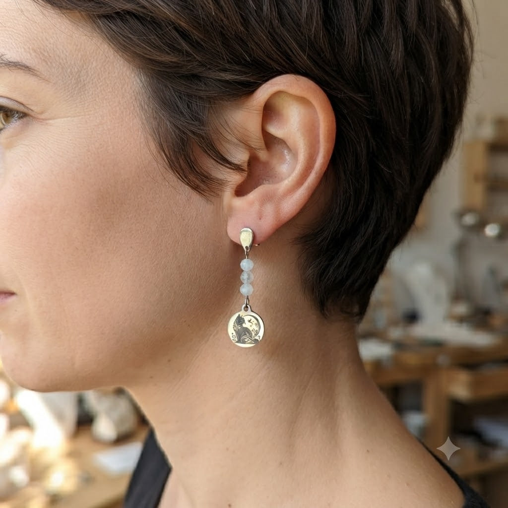 Vue de profil d'une femme portant des boucles d'oreilles pendantes motif chat avec perles naturelles.