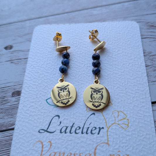 Paire de boucles d'oreilles pendantes dorées avec motif chouette gravé et perles de Lapis Lazuli sur carte de présentation L'atelier Vanessa Créa