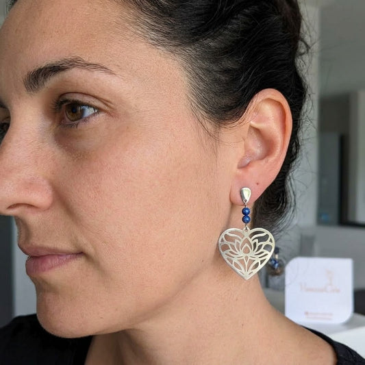 Boucles d'oreilles cœur ajouré en acier inoxydable et lapis-lazuli portées, mettant en valeur leur élégance et leur taille.