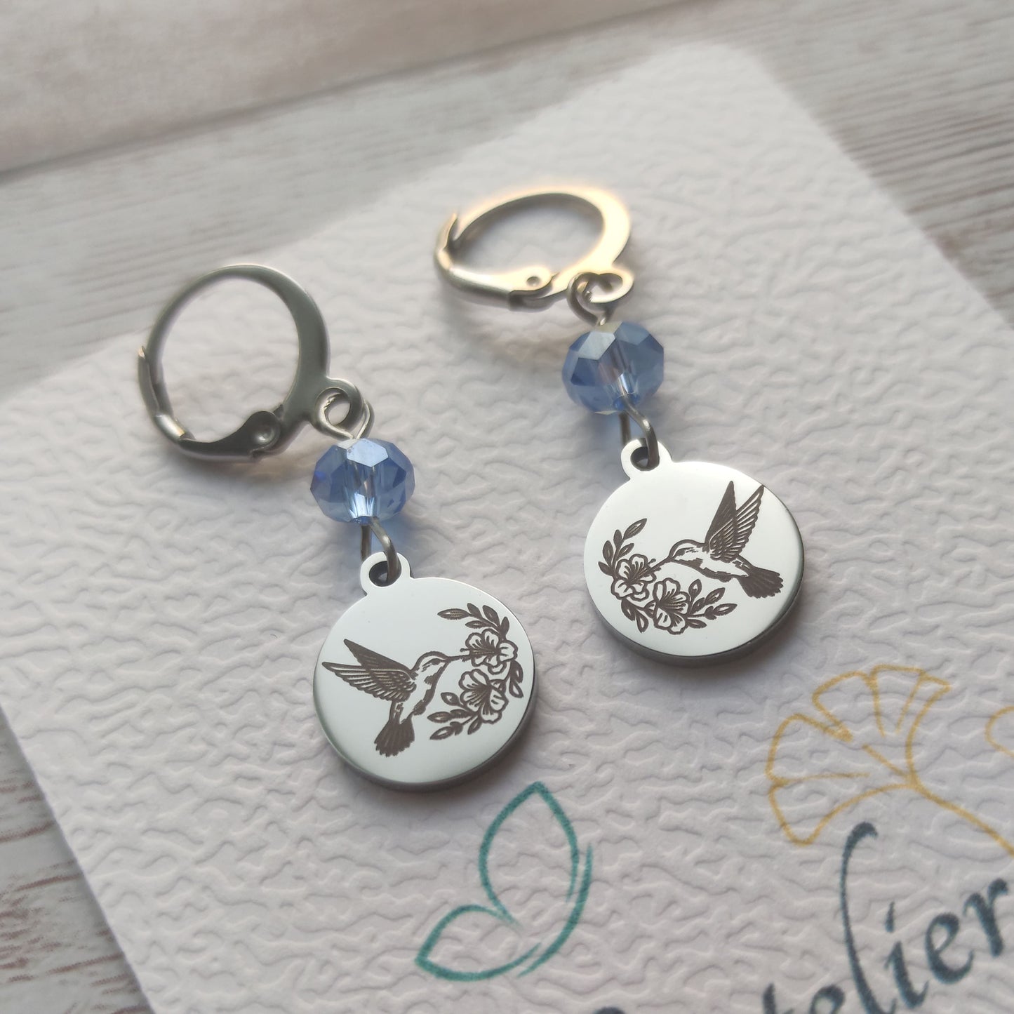 Boucles d'oreilles pendantes colibri en acier inoxydable poli miroir avec cristal à facettes et fermoir levier français.