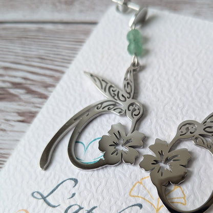 Vue de côté des boucles d'oreilles colibri argentées sur le carton de présentation.