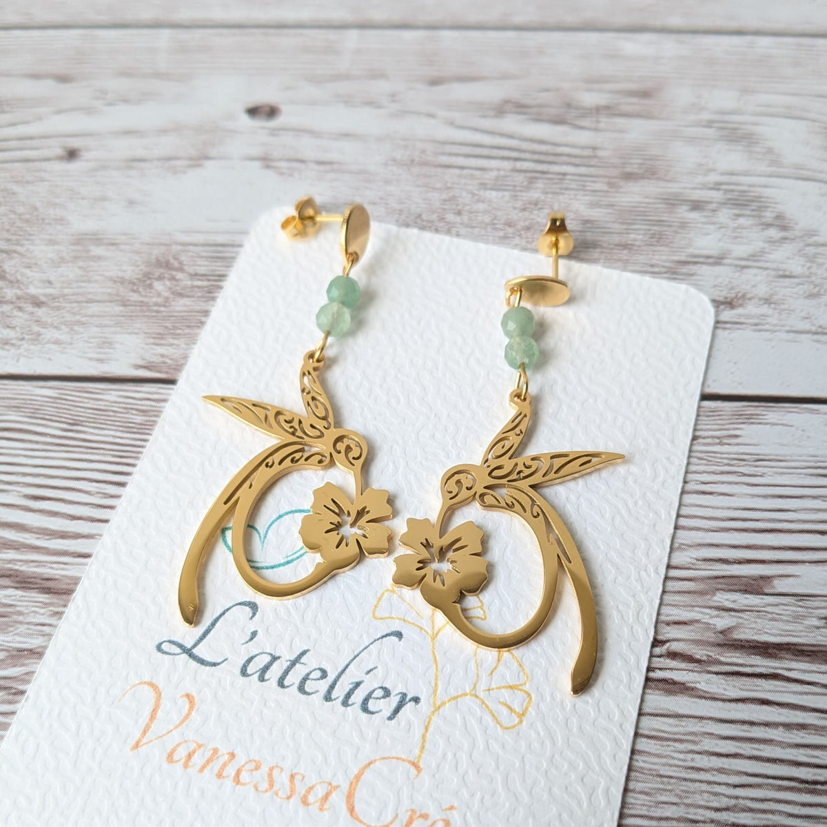 Vue détaillée des boucles d'oreilles colibri dorées avec perles naturelles.