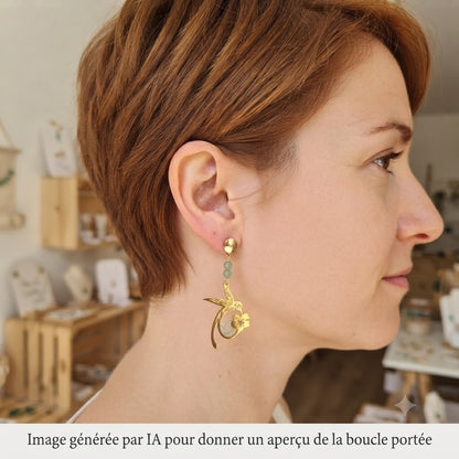 Femme portant des boucles d'oreilles pendantes colibri dorées.