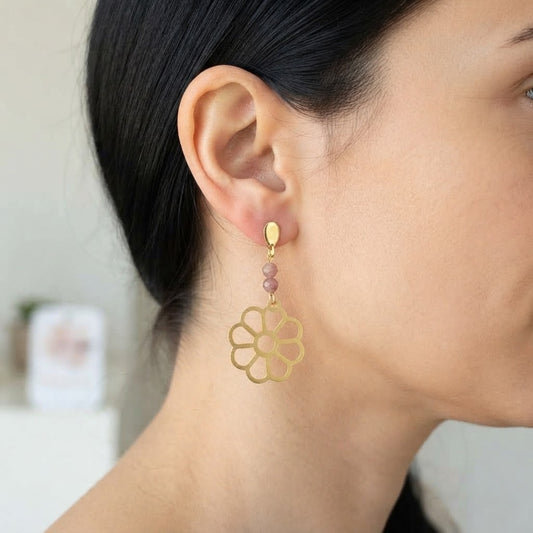 Boucles d'oreilles fleur ajourée en laiton et rhodonite portées, mettant en valeur leur élégance et leur éclat doré.