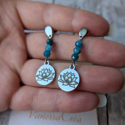 Paire de boucles d'oreilles fleur de lotus argentées avec apatite bleue, présentées en main.