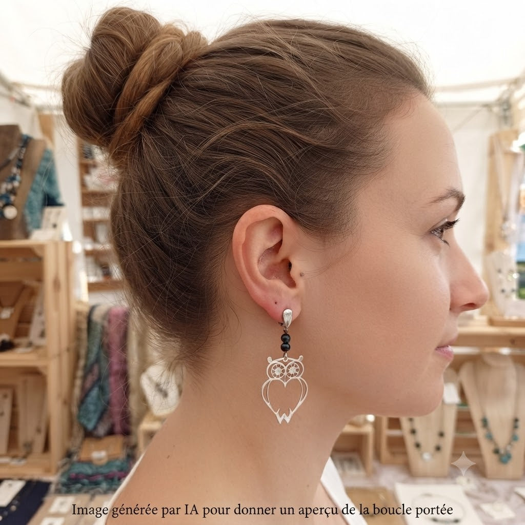 Femme portant des boucles d'oreilles pendantes hibou argenté.