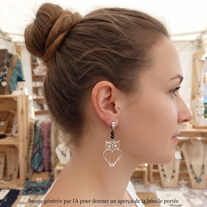 Femme portant des boucles d'oreilles pendantes hibou argenté.