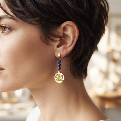 Vue de profil d'une femme portant des boucles d'oreilles pendantes dorées motif hirondelle avec perles naturelles.
