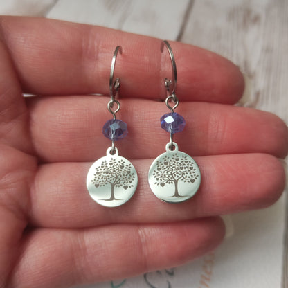 Boucles d'oreilles avec fermoir levier français, cristal à facettes bleu et médaillon rond en acier inoxydable gravé d'un arbre de vie avec cœurs.