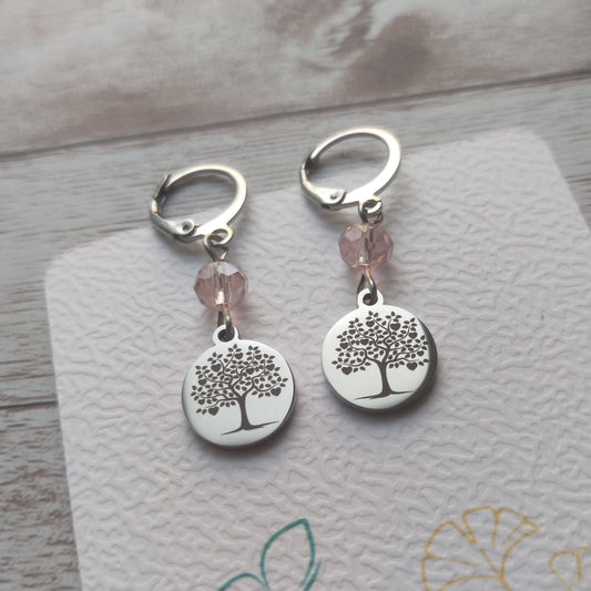 Boucles d'oreilles avec fermoir levier français, cristal à facettes rose 
et médaillon rond en acier inoxydable gravé d'un arbre de vie avec cœurs.