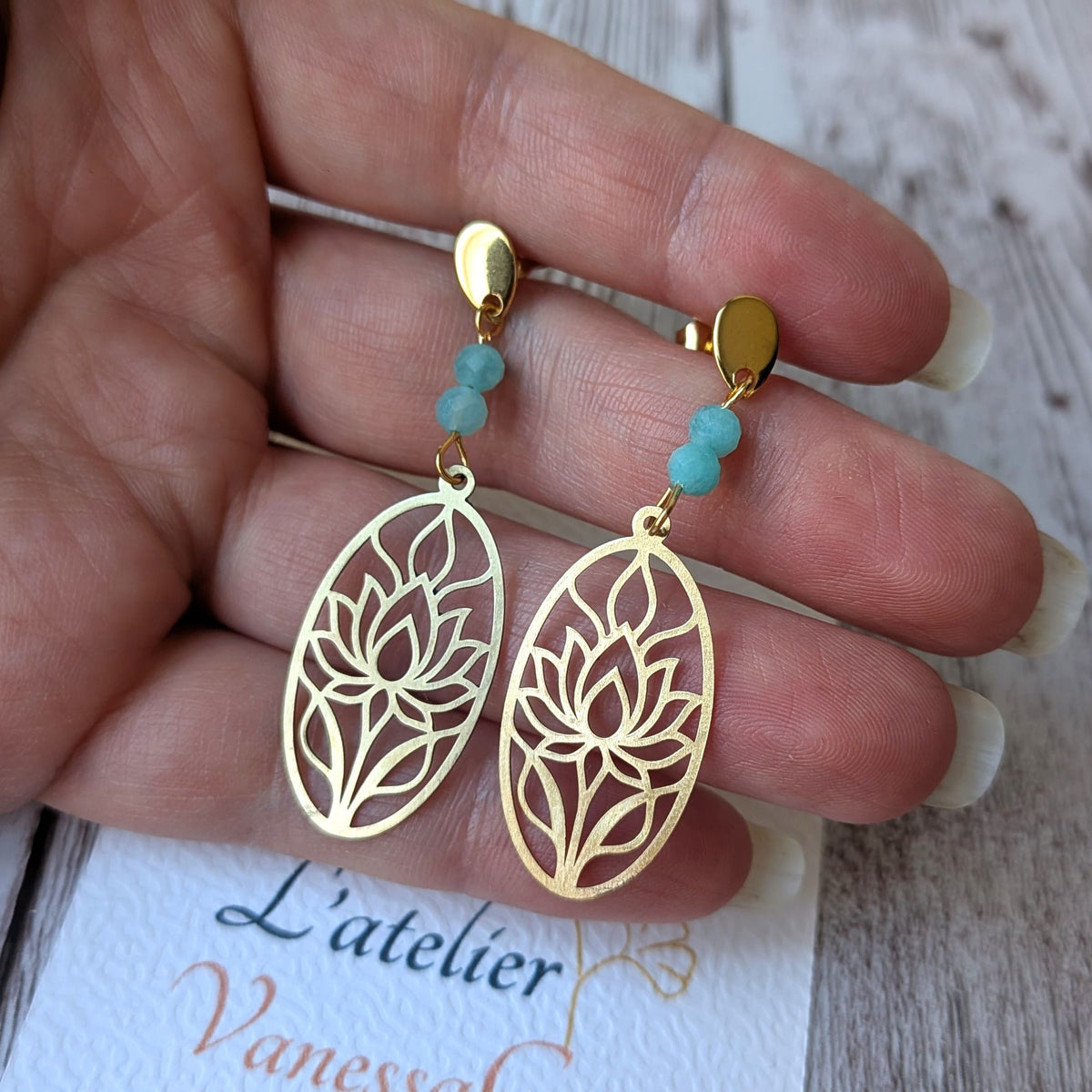Boucles d'oreilles lotus ajouré en laiton et amazonite présentées sur fond de carte de l'atelier Vanessa Créa.