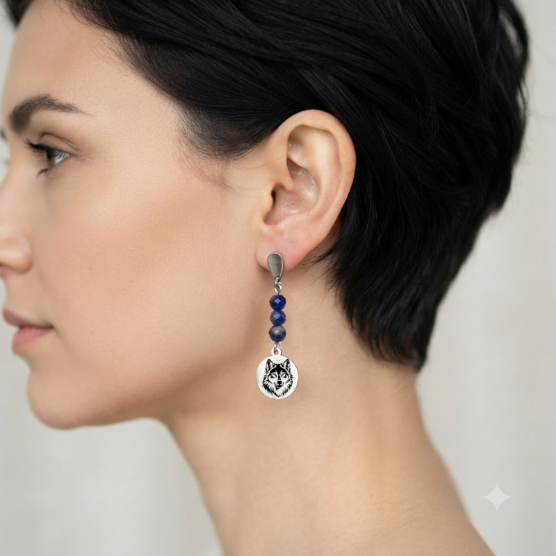 Vue de profil d'une femme portant des boucles d'oreilles pendantes motif loup avec perles naturelles.