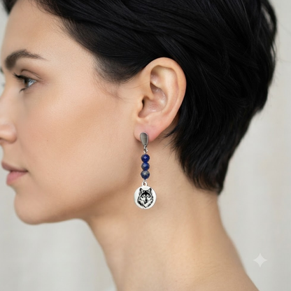 Vue de profil d'une femme portant des boucles d'oreilles pendantes motif loup avec perles naturelles.